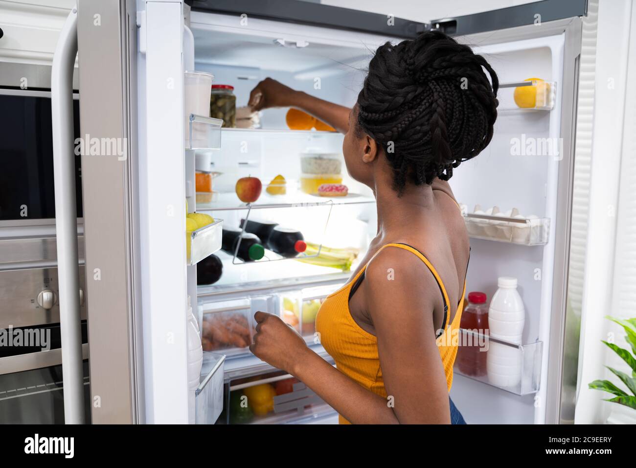 African American Woman Near Open Refrigerator Or Fridge Stock Photo
