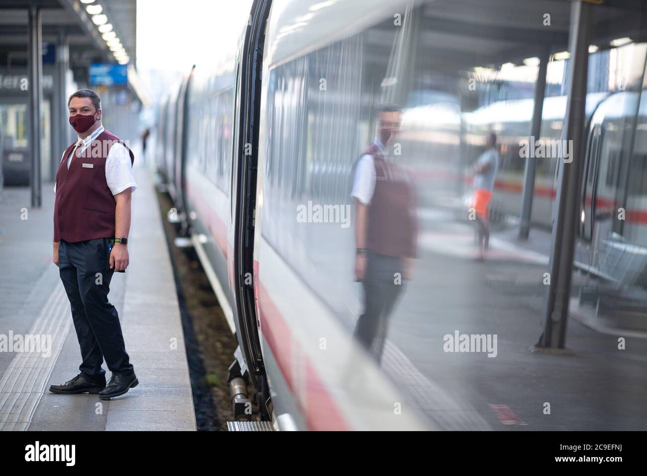 Stuttgart, Germany. 31st July, 2020. A train attendant dressed in the new clothing of the German Railways stands next to an ICE train travelling from Stuttgart to the Baltic resort of Binz. The clothing was created by the designer Guido Maria Kretschmer. Credit: Sebastian Gollnow/dpa/Alamy Live News Stock Photo