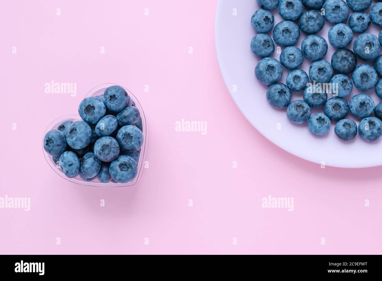 Blueberries in a heart shaped bowl, berry on a pink plate, dish. Abstract backgrounds, bright summer wallpaper. Selective focus Stock Photo