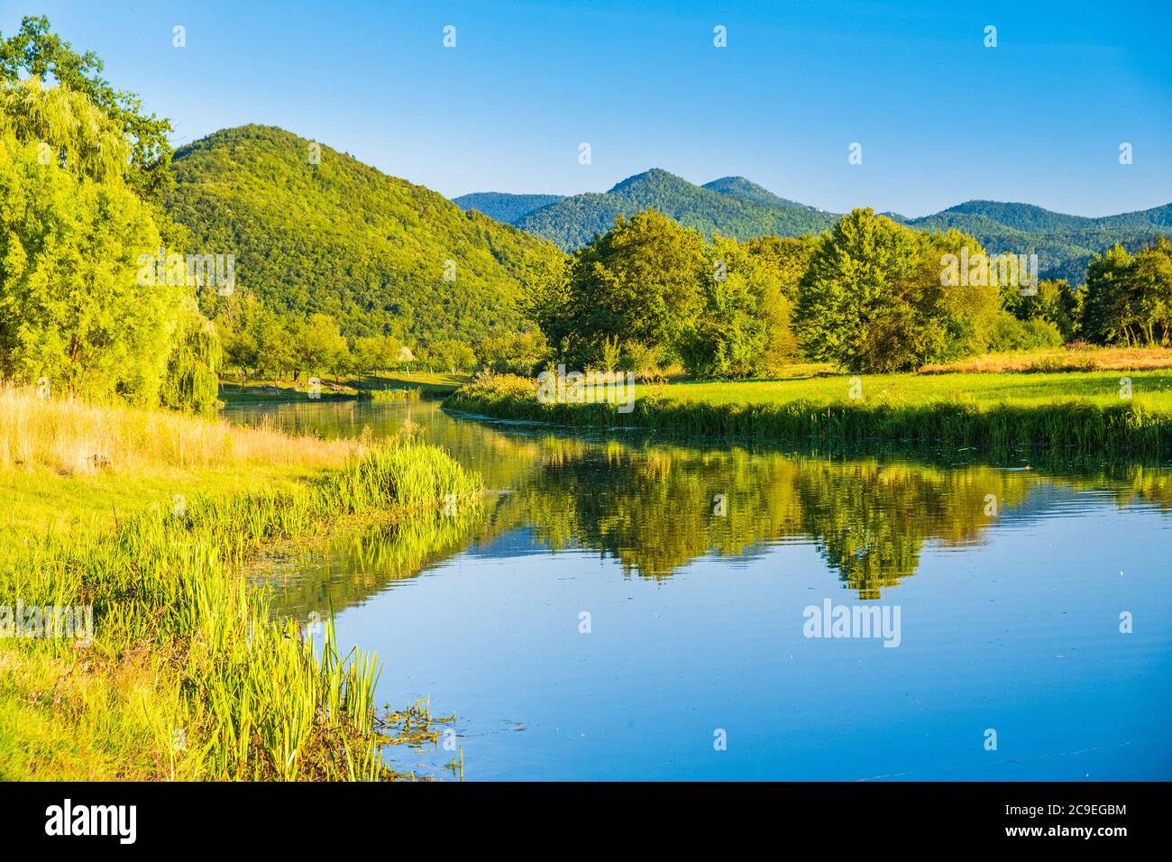 Croatia, beautiful river Gacka flowing between the green meadow fields in Lika region Stock Photo