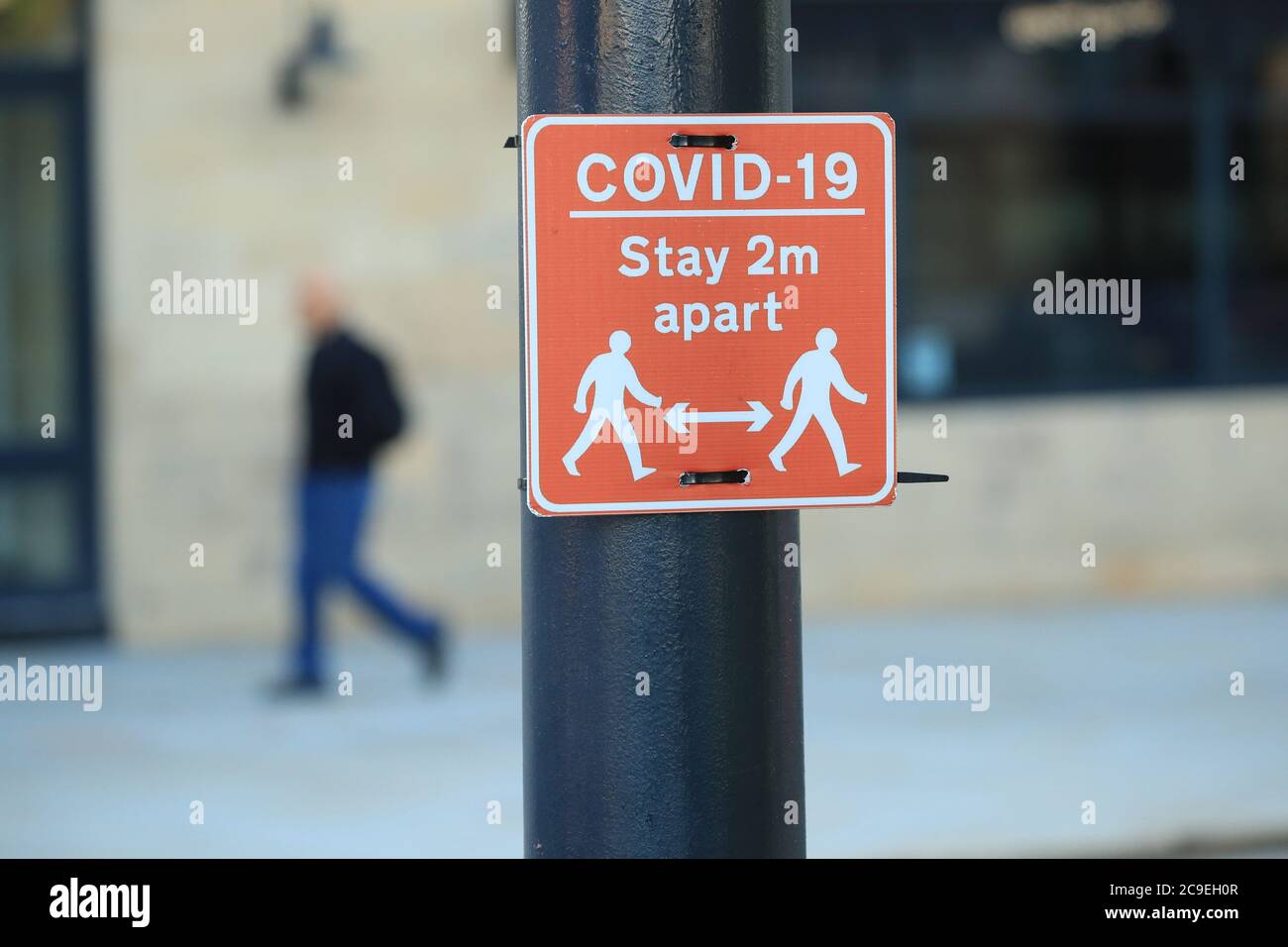 A sign advising people to stay two metres apart on a lamppost in the centre of Bradford, West Yorkshire, one of the areas where new measures have been implemented to prevent the spread of coronavirus. Stricter rules have been introduced for people in Greater Manchester, parts of East Lancashire, and West Yorkshire, banning members of different households from meeting each other indoors. Stock Photo