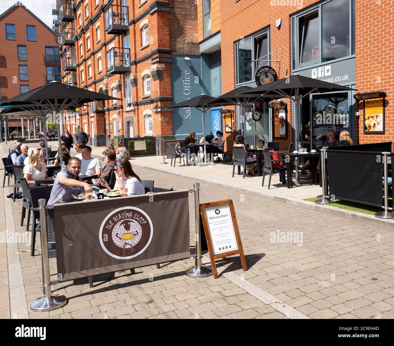 People sitting outside newly reopened cafes on the waterfront, Wet Dock, Ipswich, Suffolk, England, UK July 2020 Stock Photo
