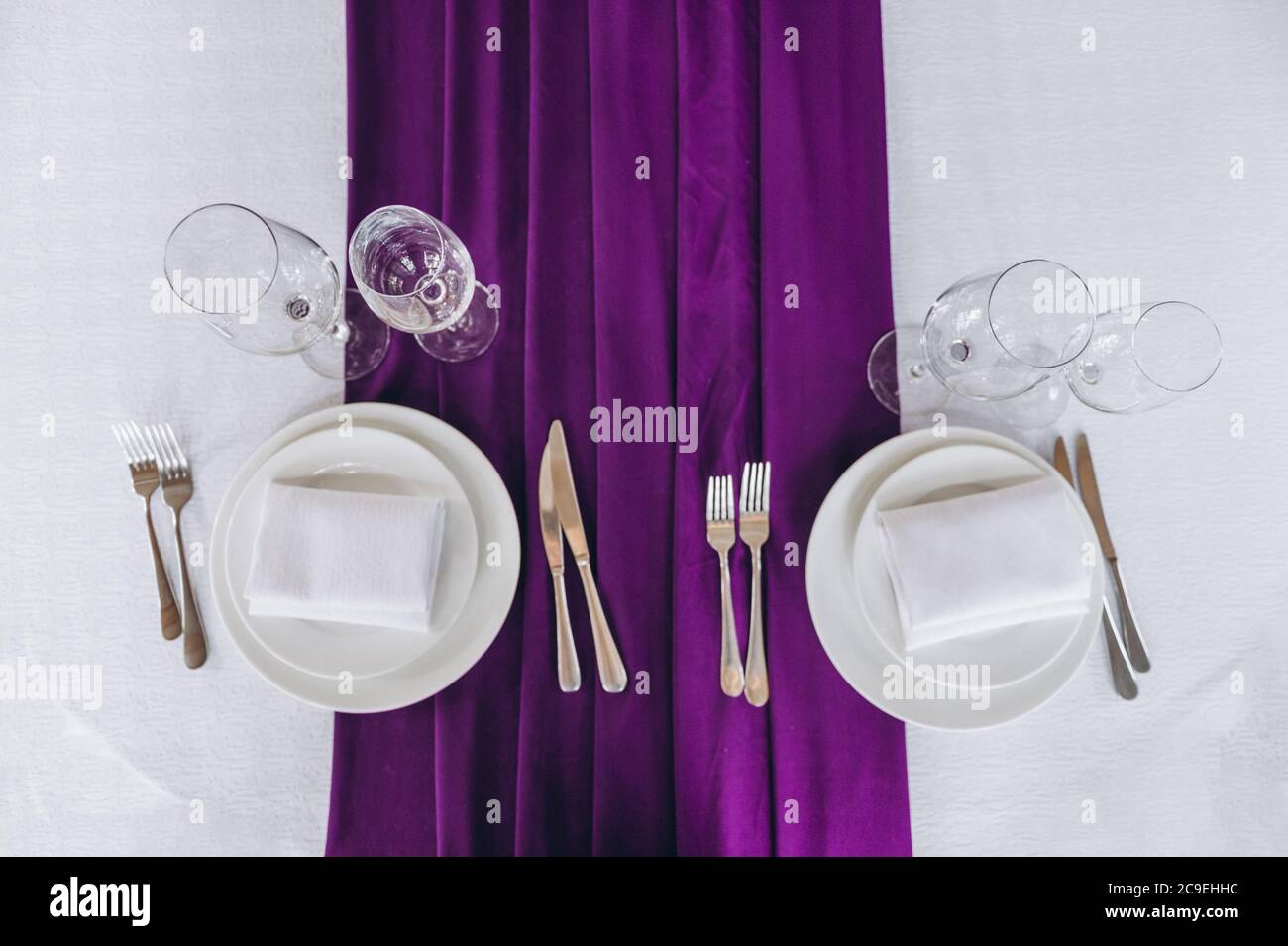 served table, with glasses, forks and knives in a restaurant with purple tablecloth. Top view Stock Photo
