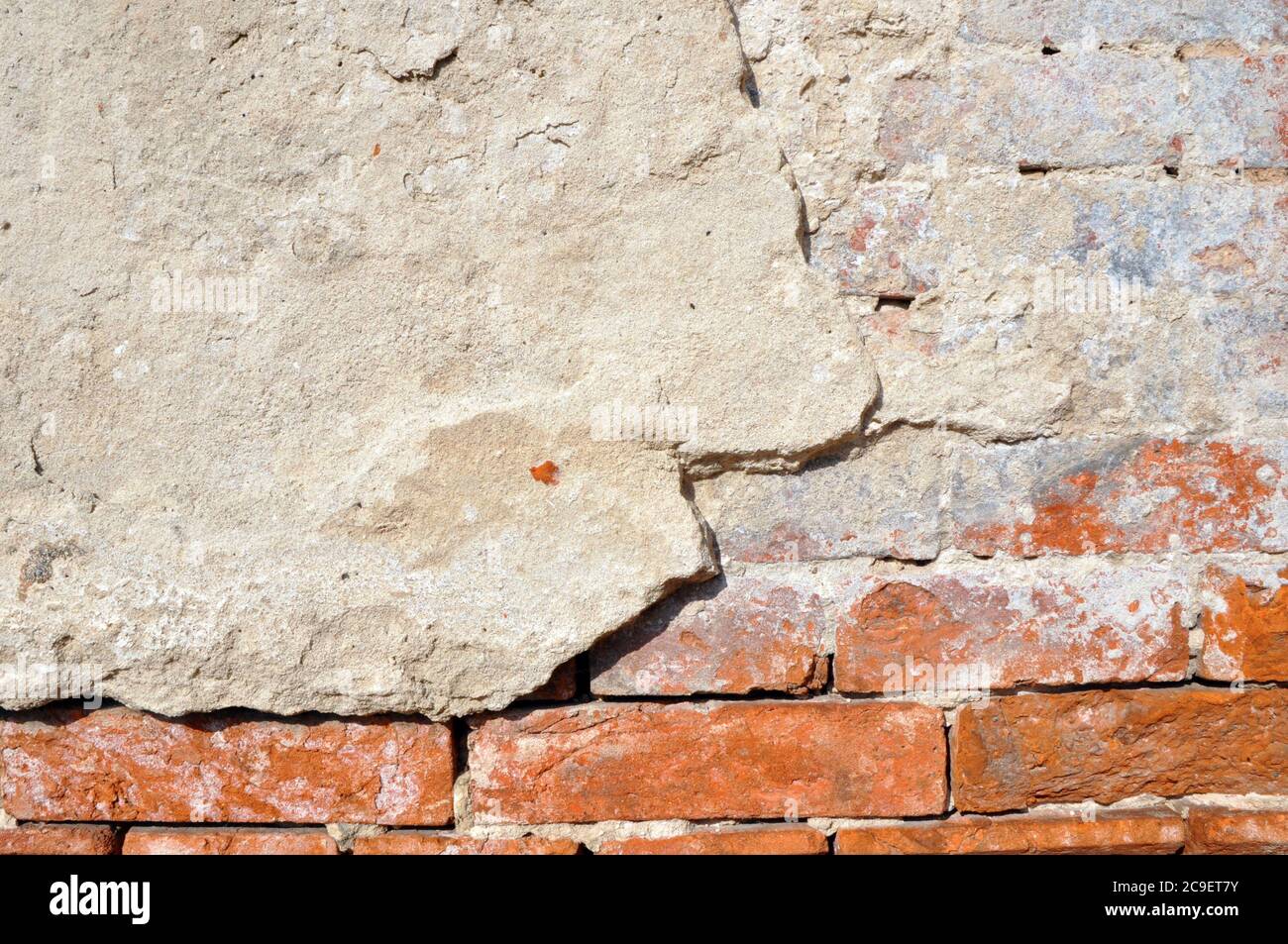 Empty old brick wall texture. Shabby facade of a building with damaged plaster. Stock Photo