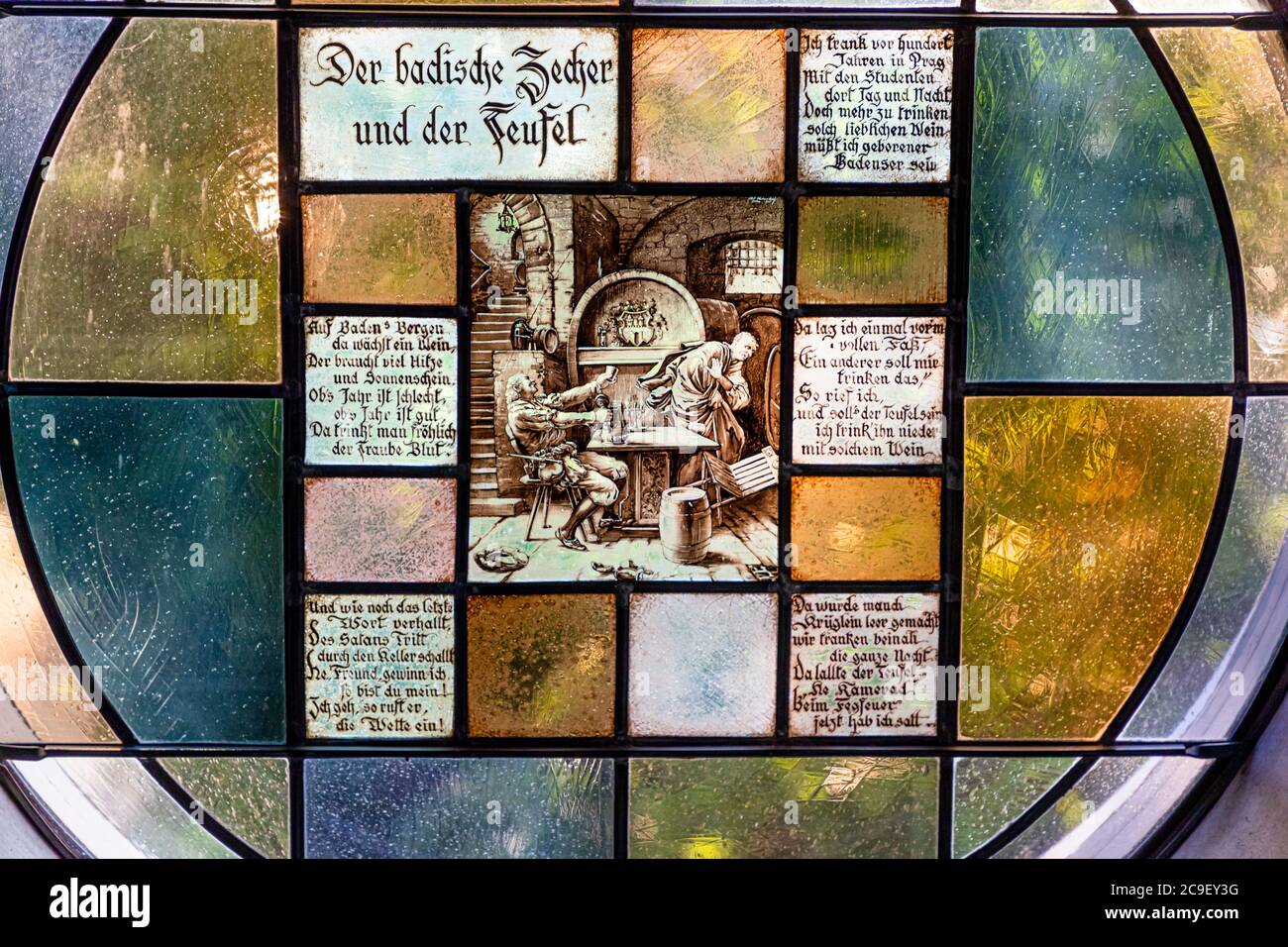 Image on a stained window depicts the Devil misleadig a drinking man. Hotel Mühle in Binzen, Germany Stock Photo
