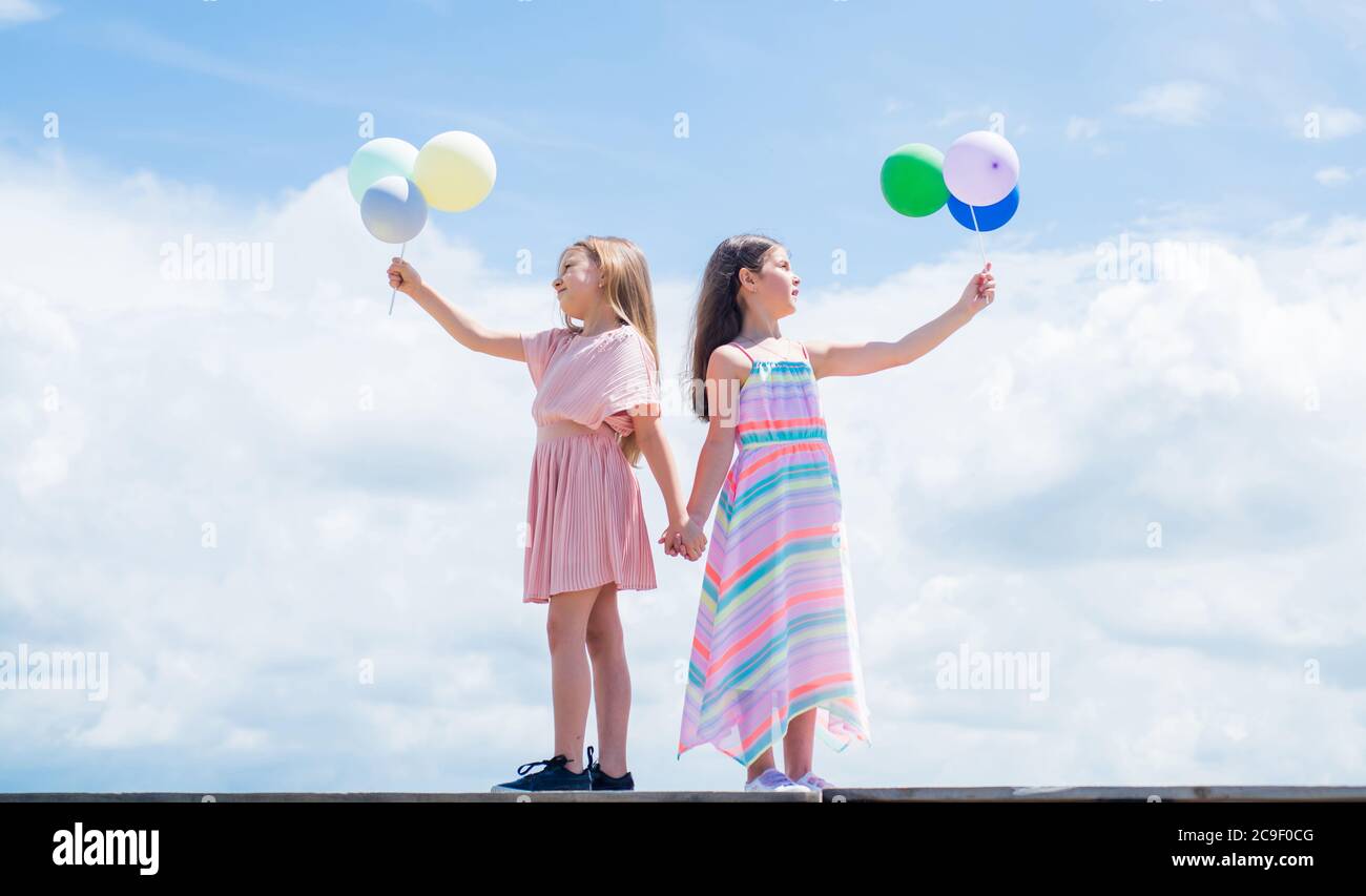 summer vacation. small girls embrace. love and support. concept of sisterhood and friendship. family bonding time. best friends with balloon. two sisters hold party balloon. happy childhood. Stock Photo