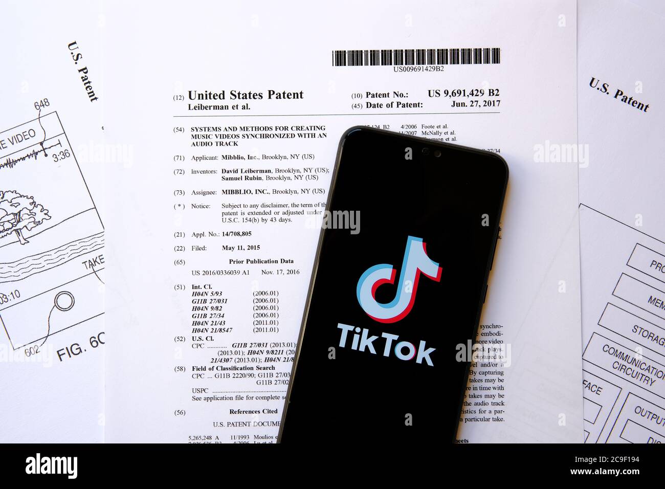 TikTok logo on the smartphone placed on a real U.S Patent No.9,691,429. The patent for which TikTok sued by rival Triller for patent infringement. Stock Photo