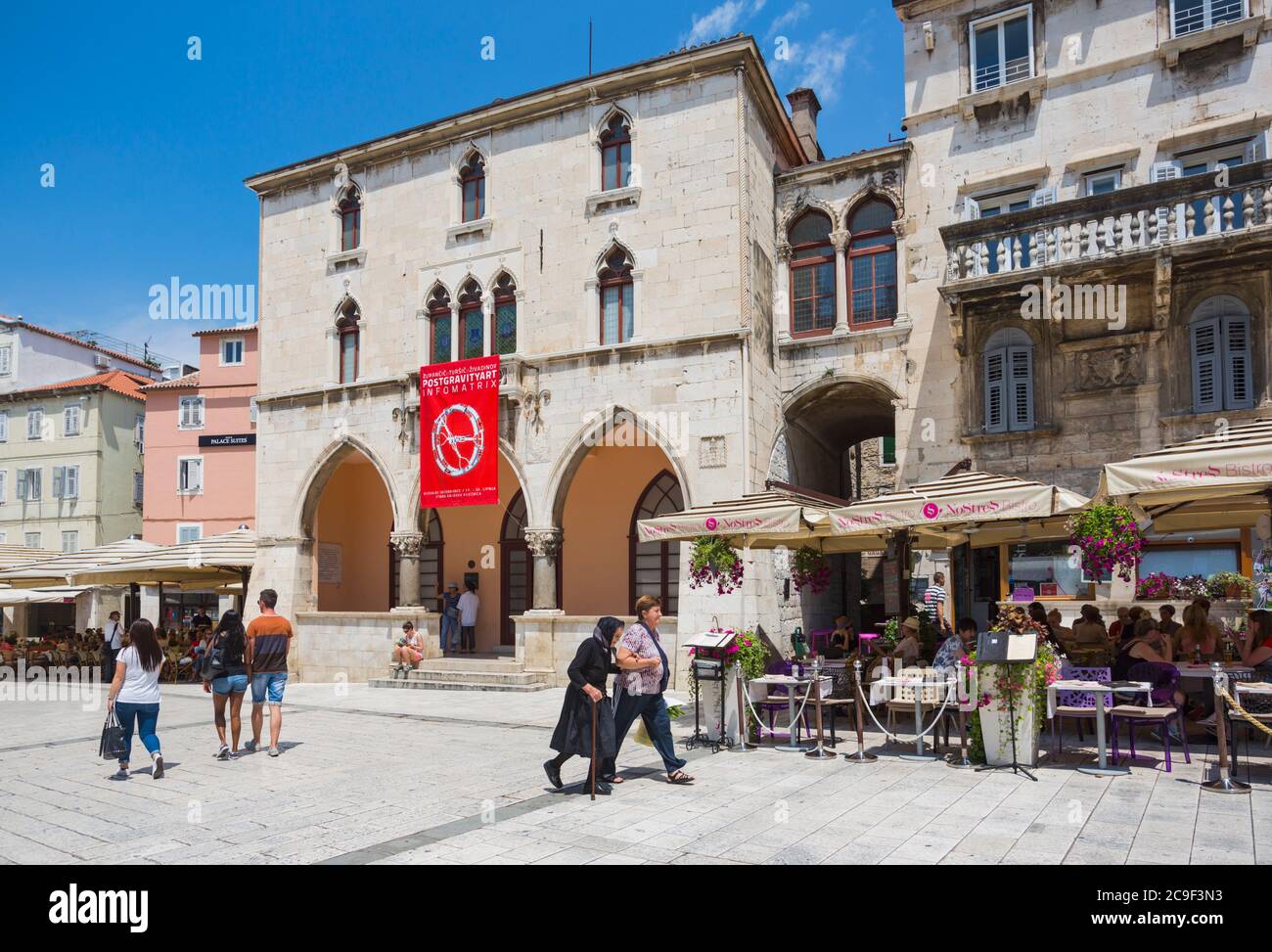 Split, Dalmatian Coast, Croatia.  People's Square.  The red banner hangs from the 15th century Renaissance Town Hall. The Historic Centre of Split is Stock Photo