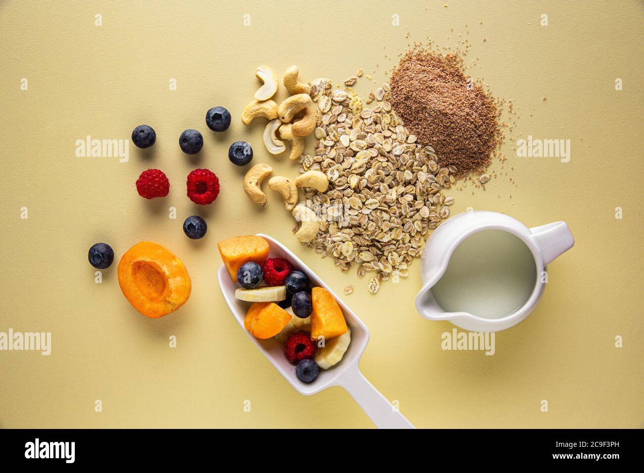 Top down view of muesli ingredients. Ripe fruit, cereal, milk, nut and
