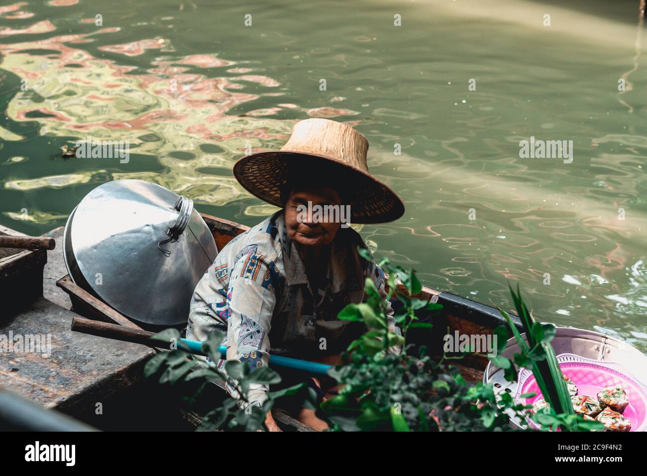 Thai woman vendor selling fruits and vegetables at Taling Chan Floating Market close to Bangkok, Thailand. Stock Photo