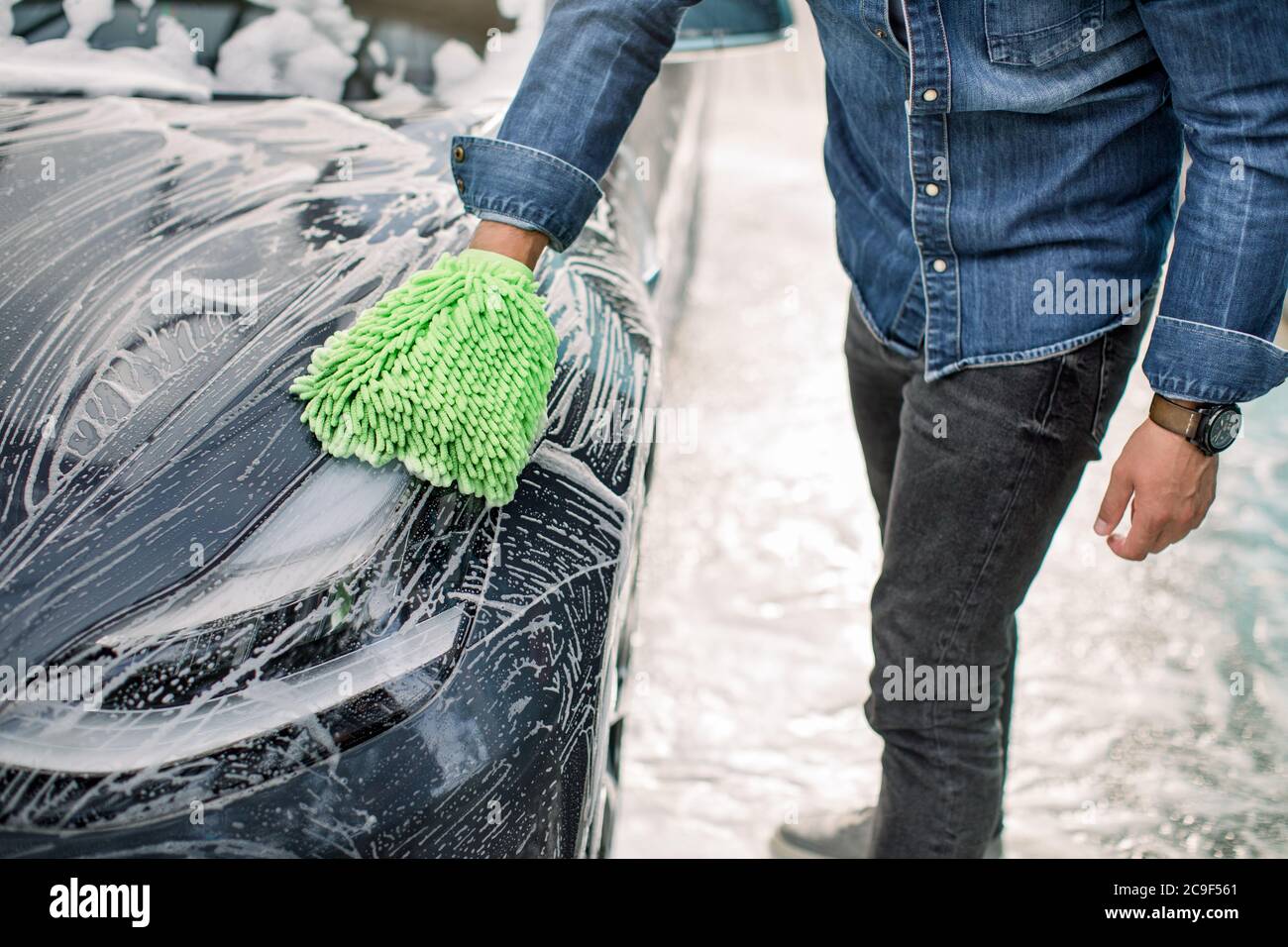 Closeup cropped image of hand of young man in jeans shirt with green sponge  washing headlight of his car at a self-serve car wash outdoors. Luxury car  Stock Photo - Alamy