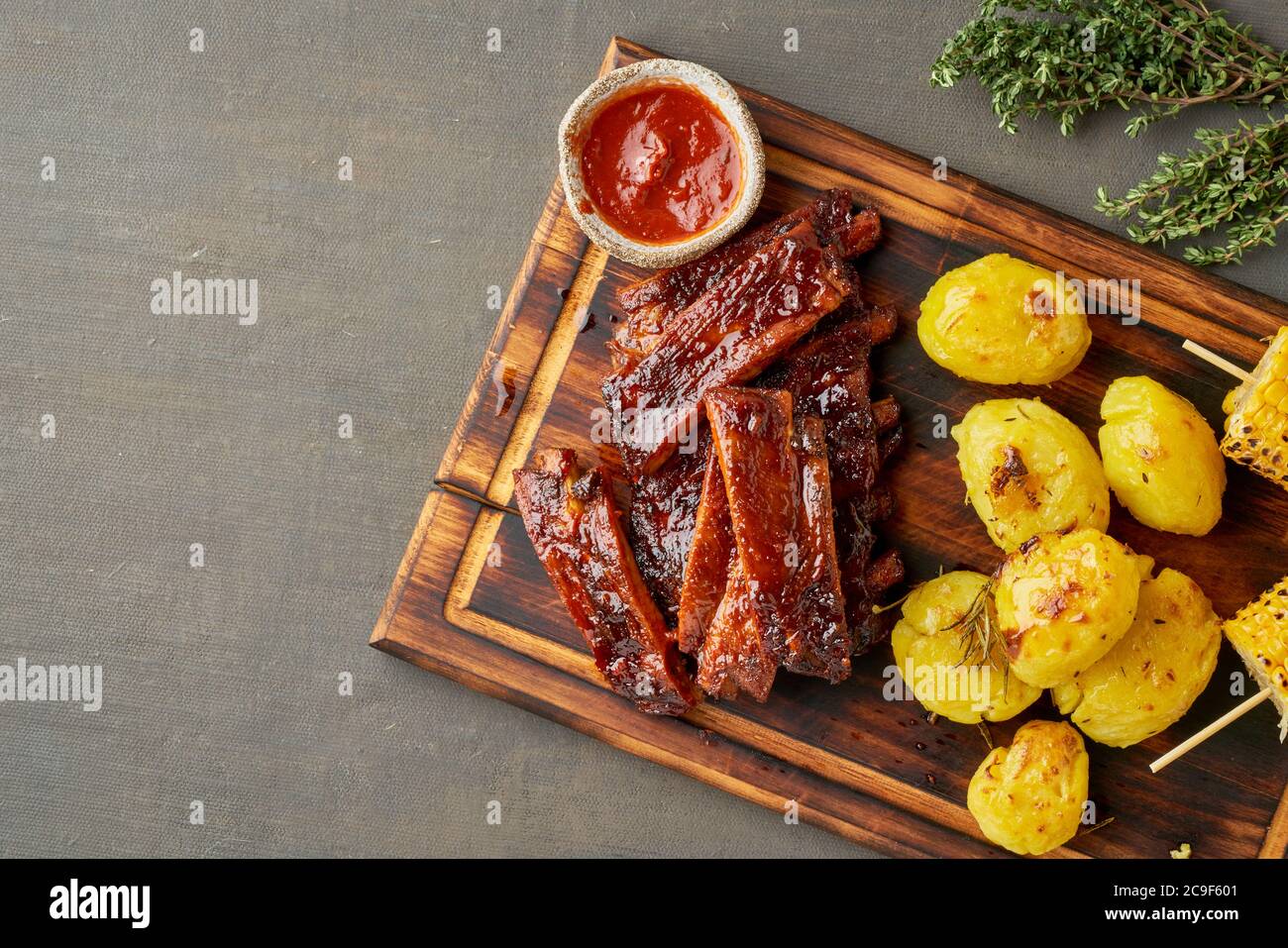 Spicy barbecue pork ribs, corn ears and crushed smashed potatoes