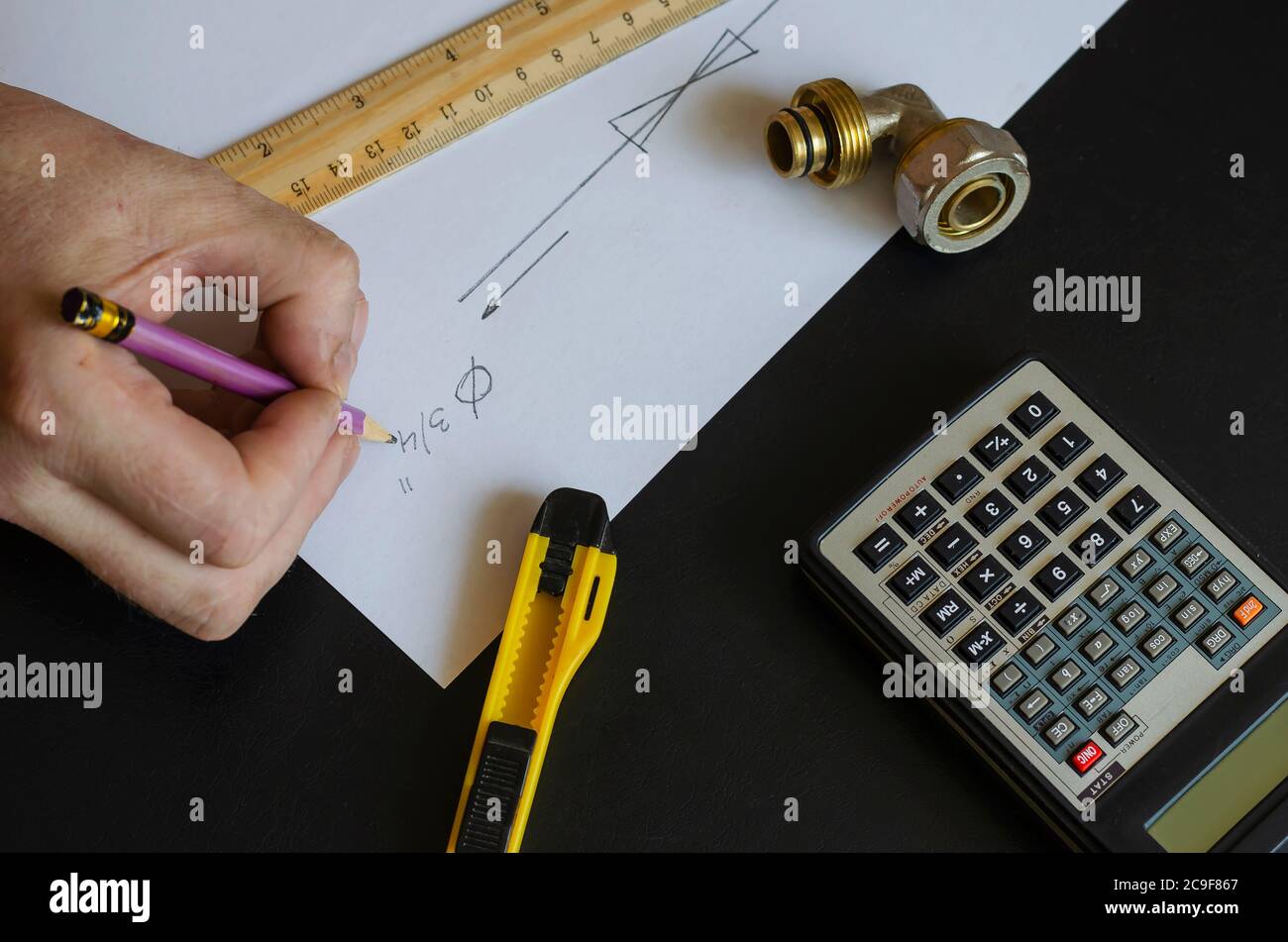 A male hand draws a diagram of home plumbing. Plumber makes the ...