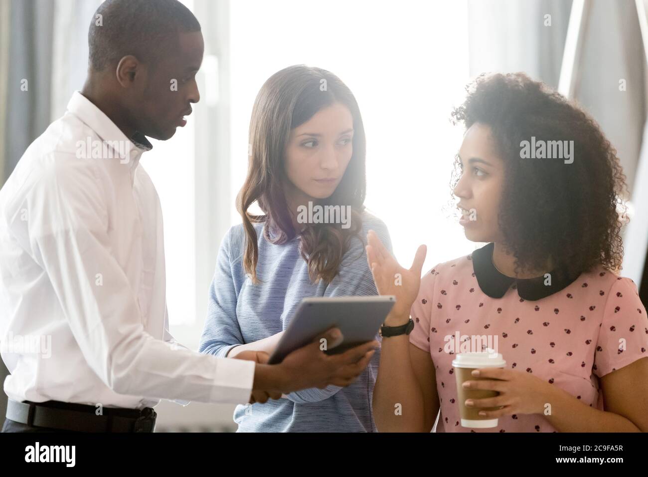 Diverse colleagues employees discussing project, using computer tablet Stock Photo