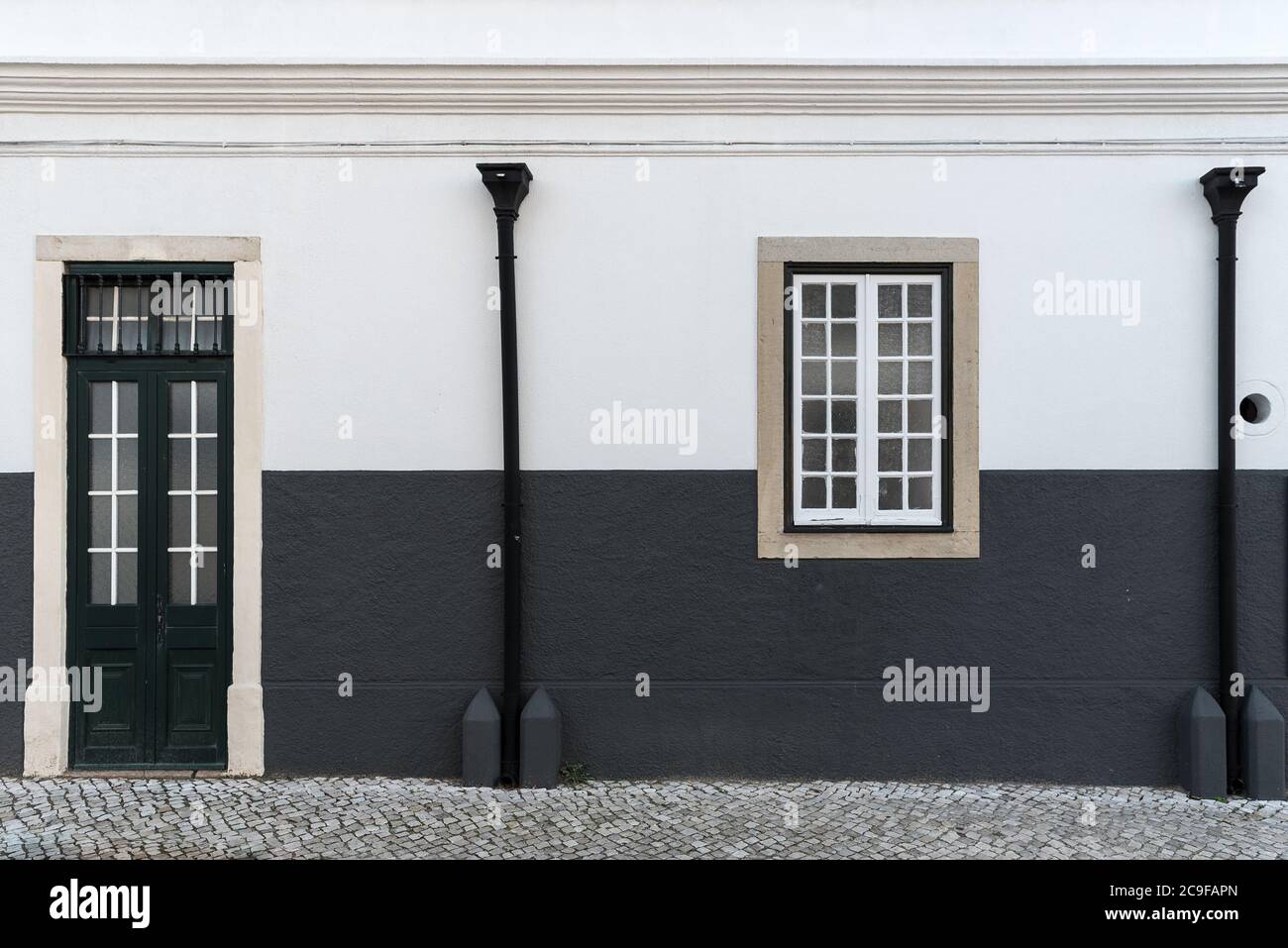 Architectural detail close-up of black and traditional white exterior facade street house with narrow street entrance through door single window and r Stock Photo