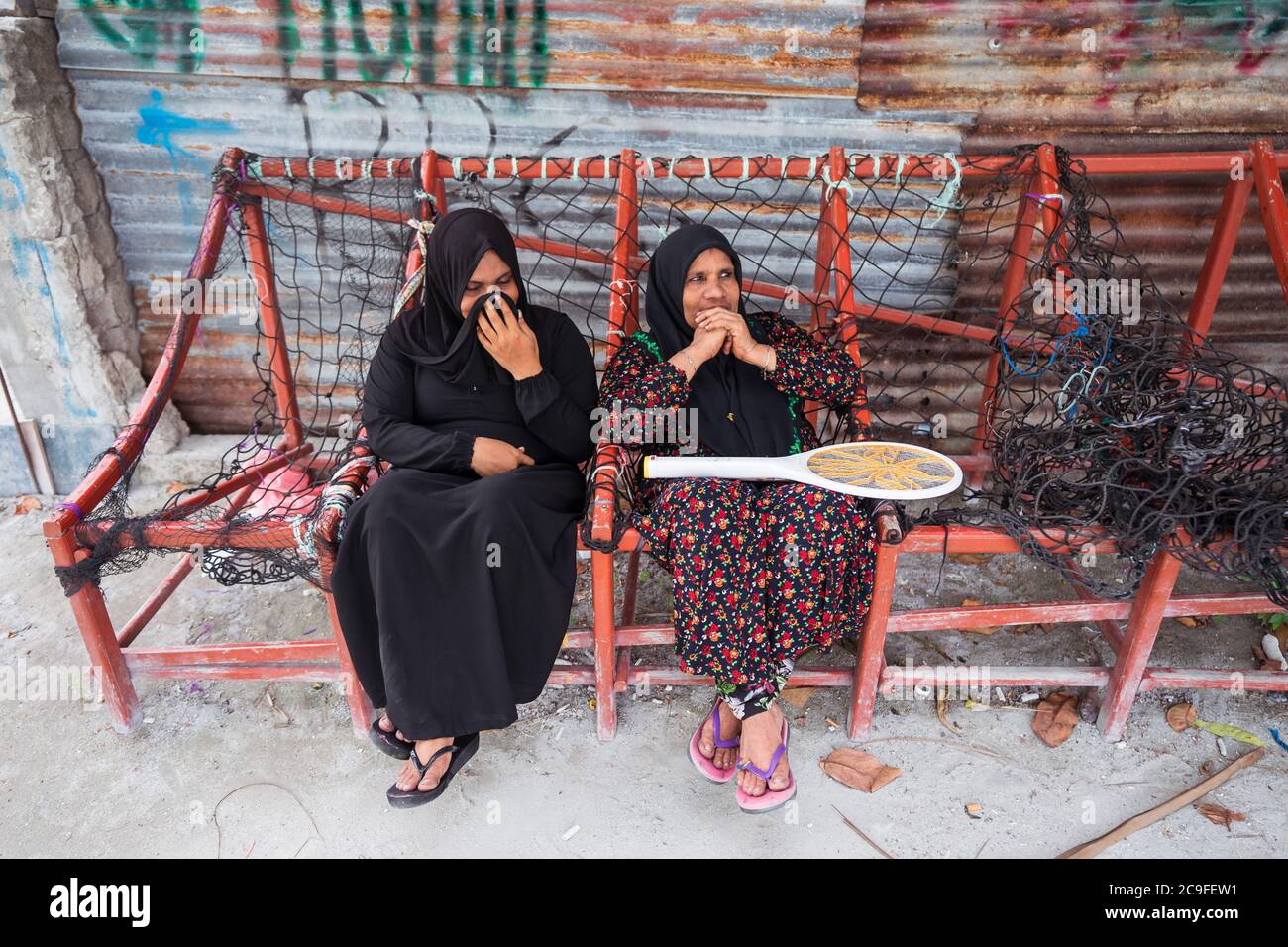 Bodufolhudhoo / Maldives - August 17, 2019: muslim women with black hijab sitting on traditional maldivian bench made with ropes Stock Photo