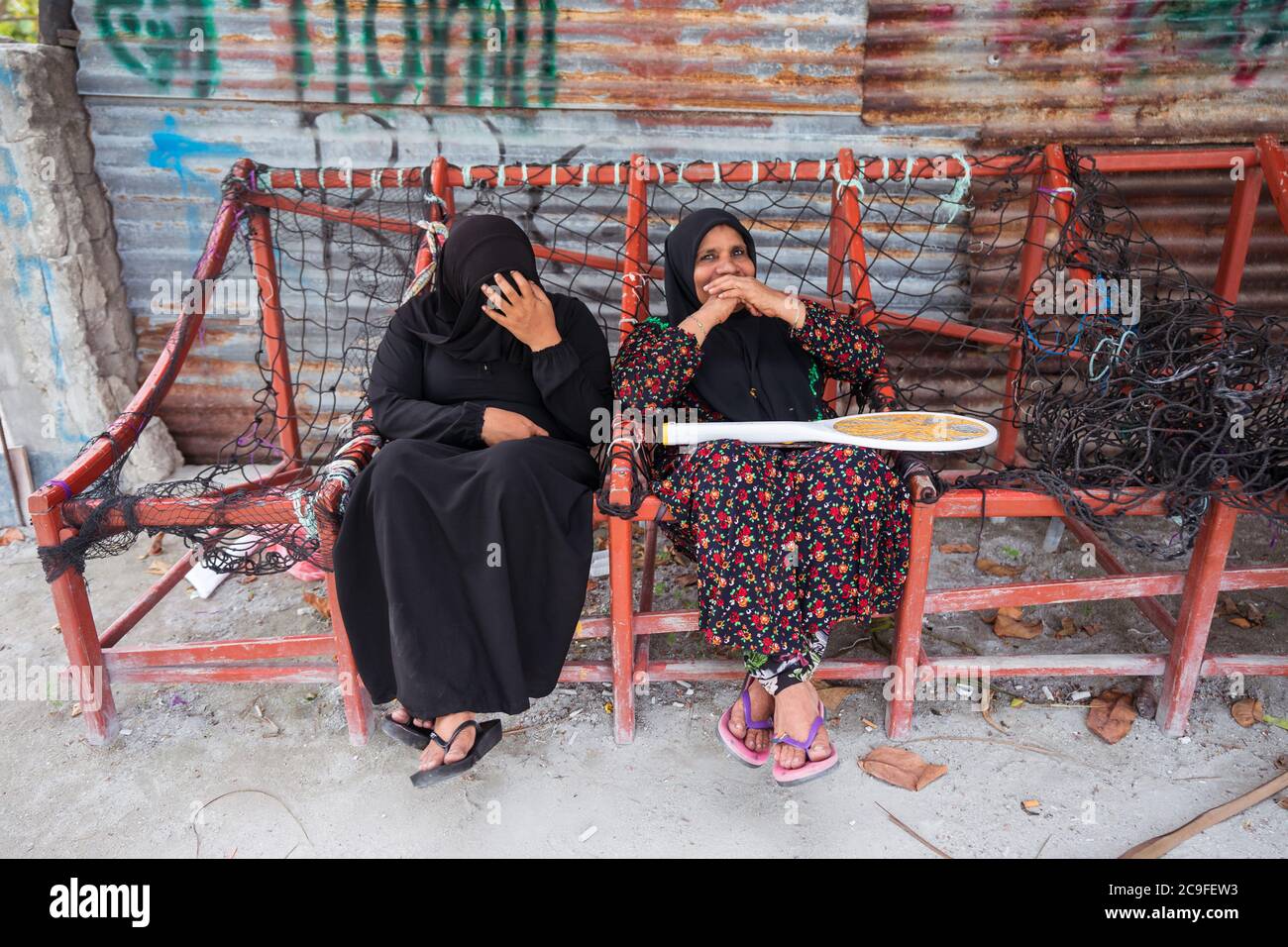 Bodufolhudhoo / Maldives - August 17, 2019: muslim women with black hijab sitting on traditional maldivian bench made with ropes Stock Photo