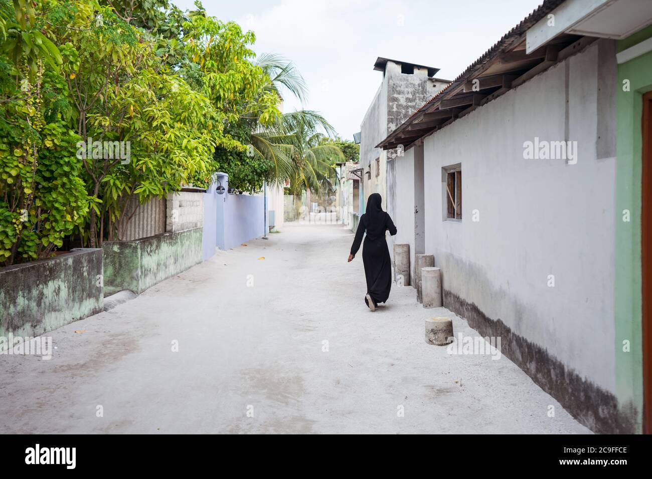 Unrecognizable Young Muslim woman in sand street in Bodufolhudhoo island village, Maldives Stock Photo