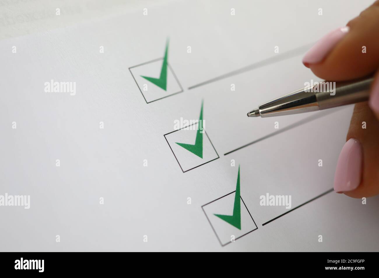 Woman's hand holds pen and marks green check marks in document Stock ...