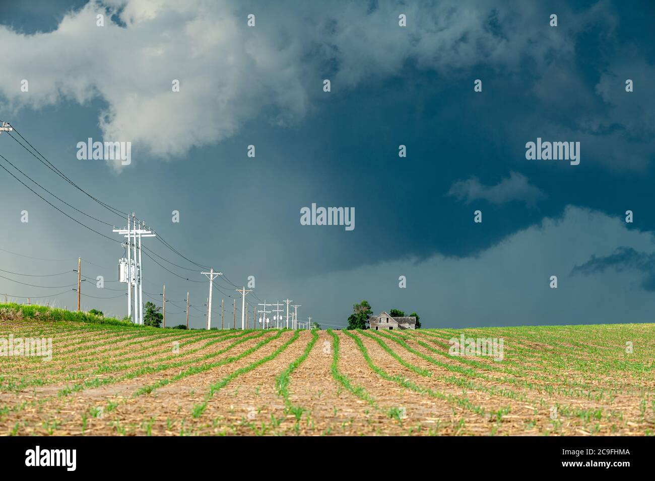 Panorama of a massive storm system, which is a pre-tornado stage, passing over a farm in the Great Plains. Stock Photo