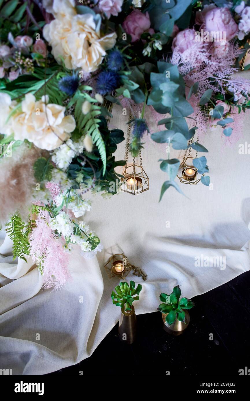 Wedding decoration, floristry. Succulents in gold vessels near the table with a light tablecloth. Stock Photo