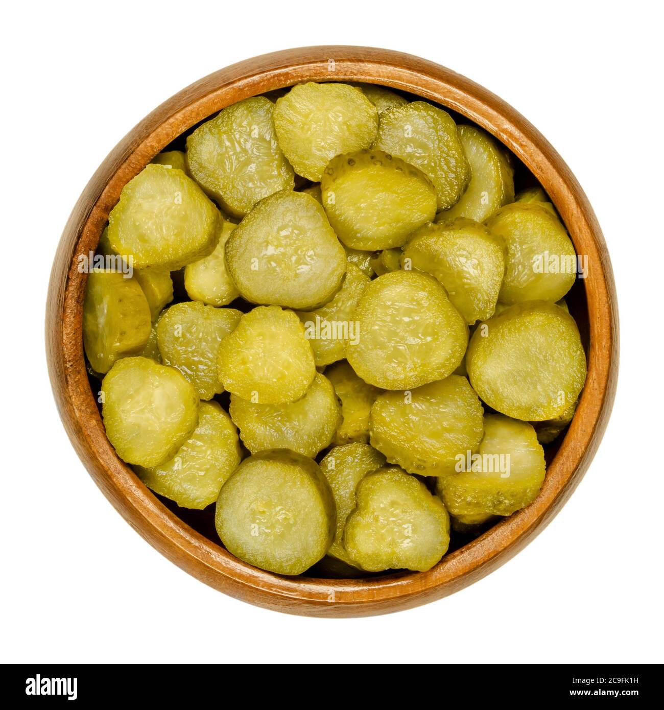 Pickled cucumber discs, also known as pickle or gherkin, in wooden bowl. Small pickled cucumbers with bumpy skin, sliced. Baby pickles. Close-up. Stock Photo