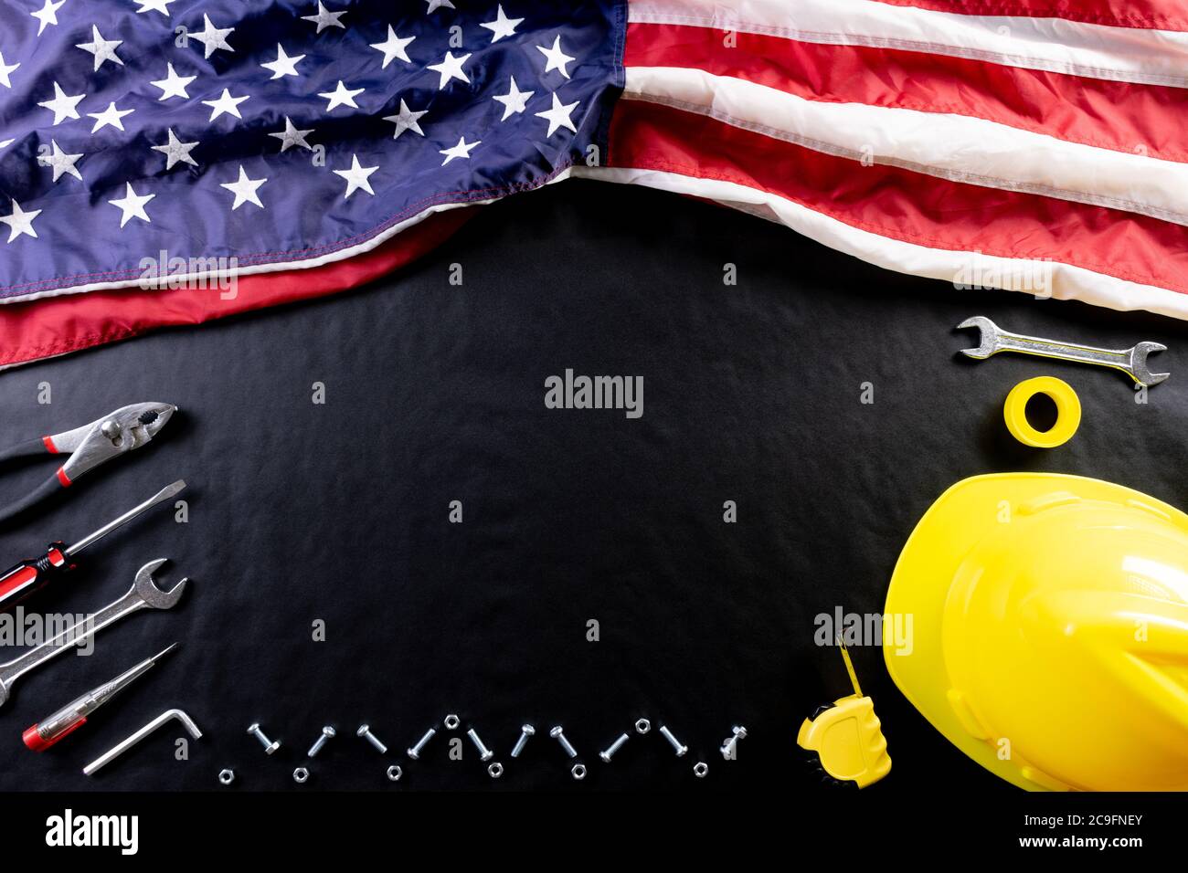 Happy Labor day concept. American flag on dark black background with different construction tools. Copy space for text. Stock Photo