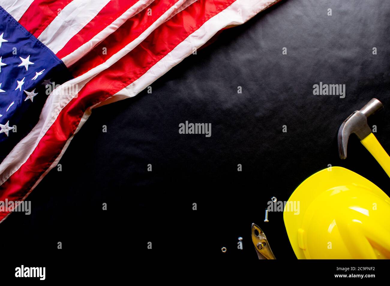Happy Labor day concept. American flag on dark black background with different construction tools. Copy space for text. Stock Photo