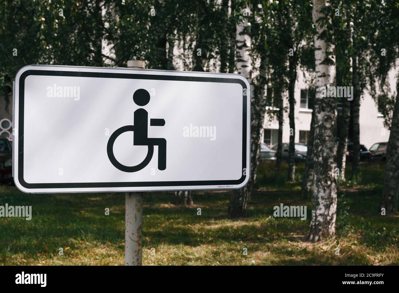 Disabled parking lot sign with residential building and birch trees on background Stock Photo