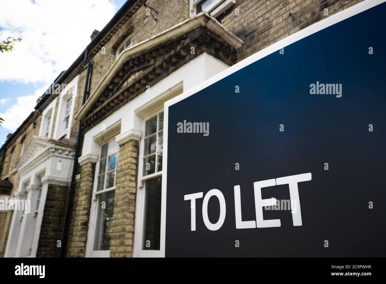 Estate agency 'To Let' sign board on street of British houses with space for text Stock Photo