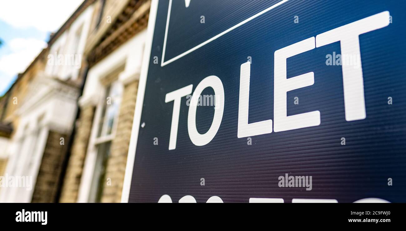 Estate agency 'To Let' sign board on street of British houses with space for text Stock Photo