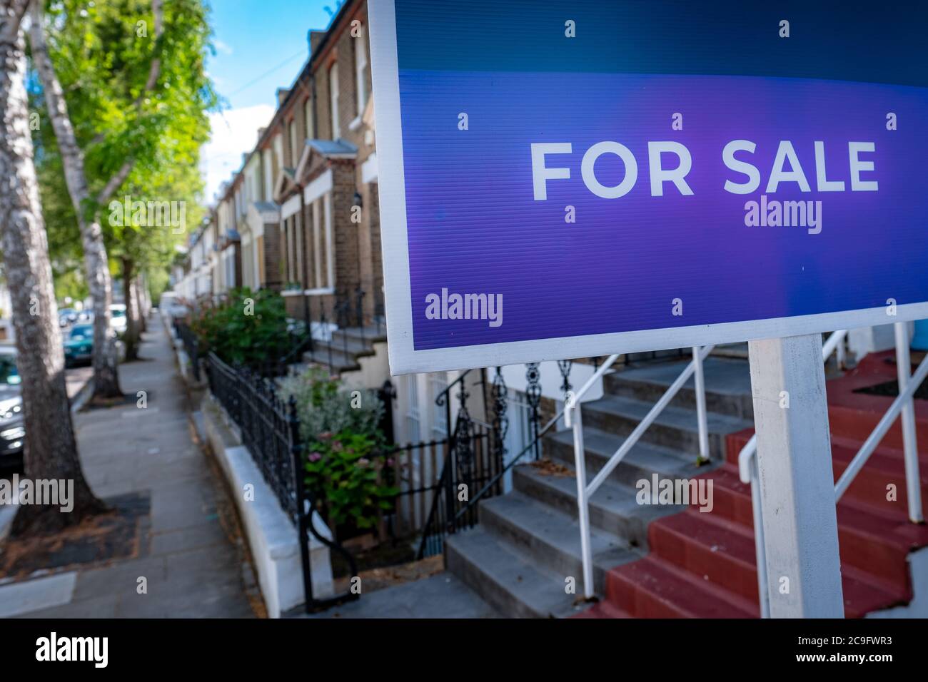 'FOR SALE' estate agency sign on street of houses Stock Photo
