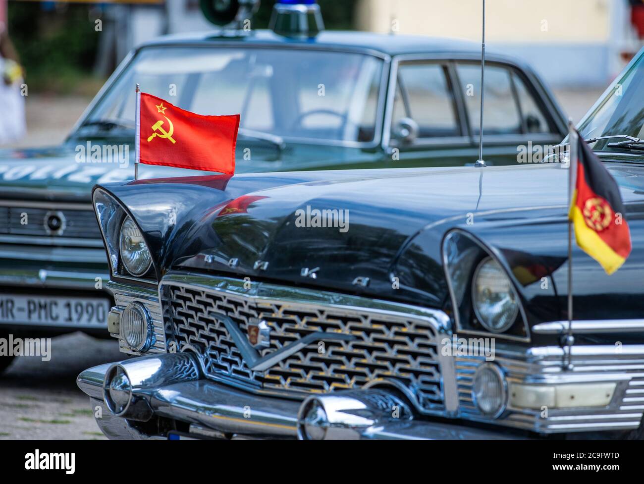 Beuster, Germany. 24th July, 2020. The flags of the Soviet Union and the GDR are waving on a Soviet Chaika limousine which is on the blue light days in the blue light museum Beuster on the exhibition area. Despite corona protection measures, the blue light museum on the Elbe celebrates its museum week and shows the collection of historical fire brigade, police and military technology. Credit: Jens Büttner/dpa-Zentralbild/ZB/dpa/Alamy Live News Stock Photo