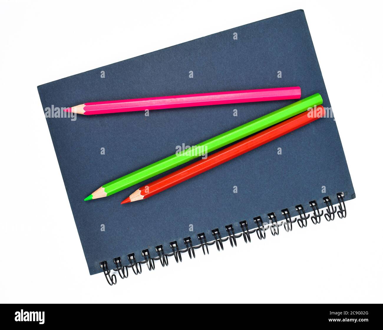 Three different colored wood pencil crayon placed on top of a blue paper diary Stock Photo