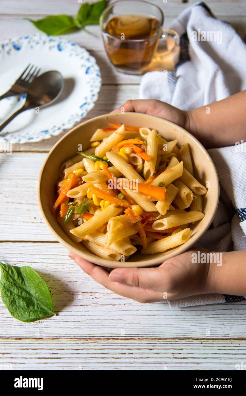 Ready to eat cooked pasta served in a bowl and tea on a background Stock Photo