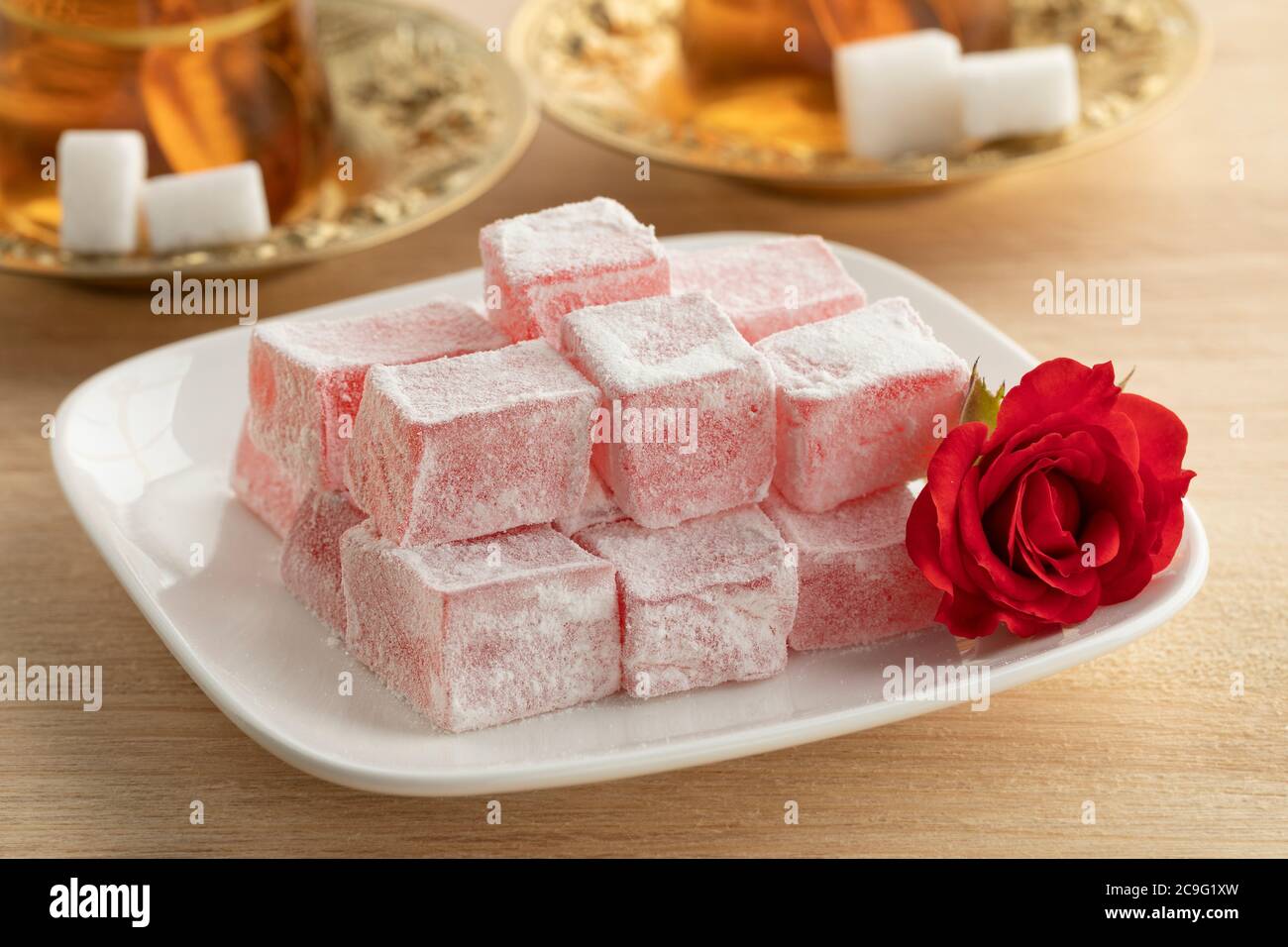 Turkish rose delight on a white dish, a fresh rose and tea Stock Photo