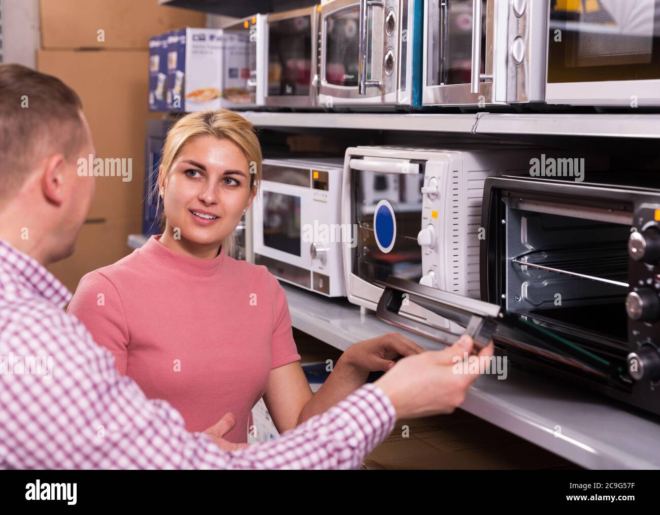 happy adult couple choosing new microwave for kitchen in furniture store Stock Photo