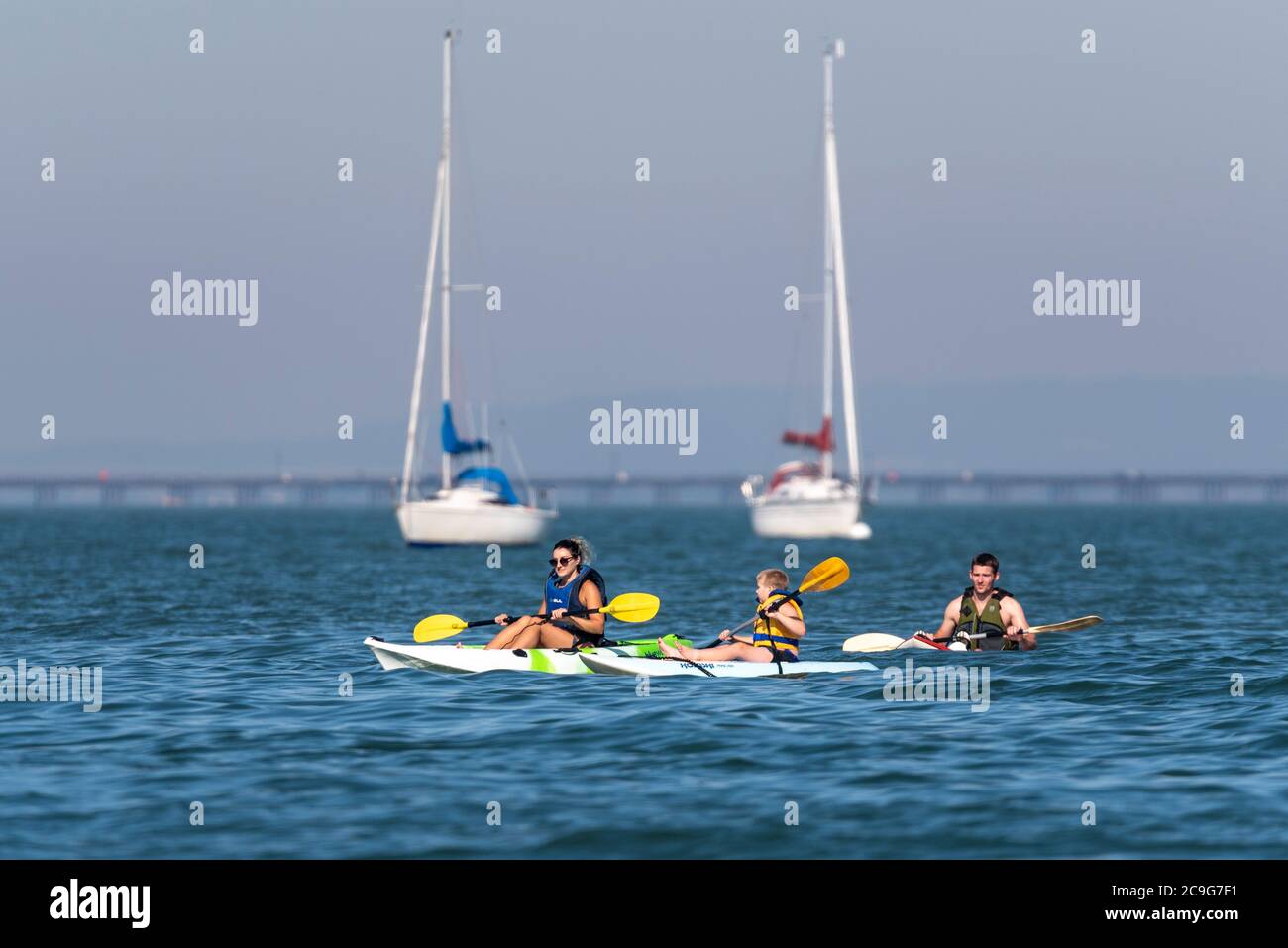 Family paddling canoes in the Thames Estuary off Thorpe Bay, Southend