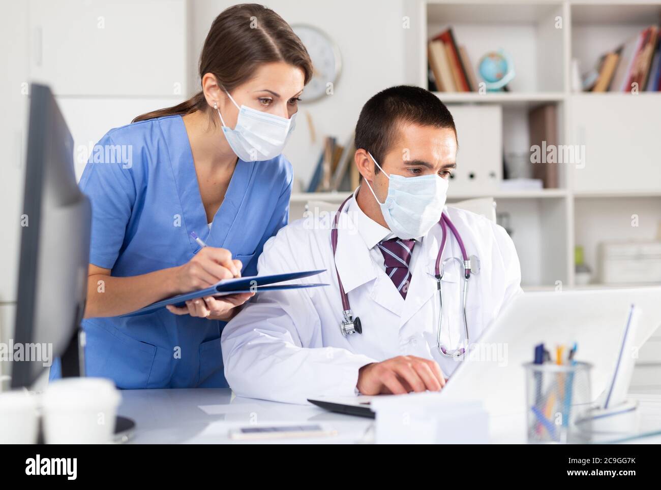 Additional Work Doctor Experienced doctor working in office with female assistant, filling up ...