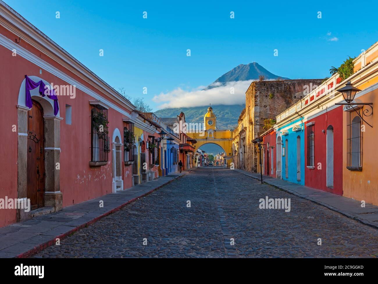 Cityscape of Antigua city at sunrise with Santa Catalina arch and Agua volcano, Guatemala. Stock Photo