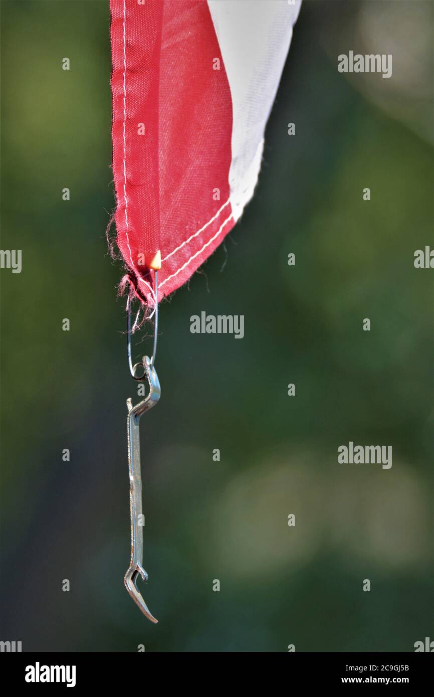 Can and bottle opener being used as weight to keep USA flag from flapping in the wing with a baby safety pin Stock Photo