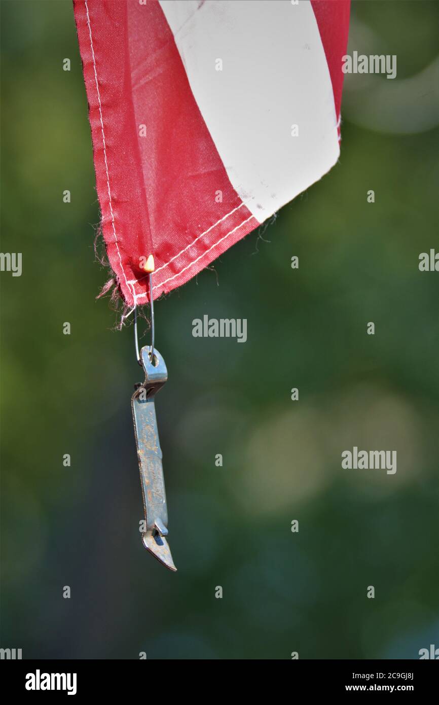 Can and bottle opener being used as weight to keep USA flag from flapping in the wing with a baby safety pin Stock Photo