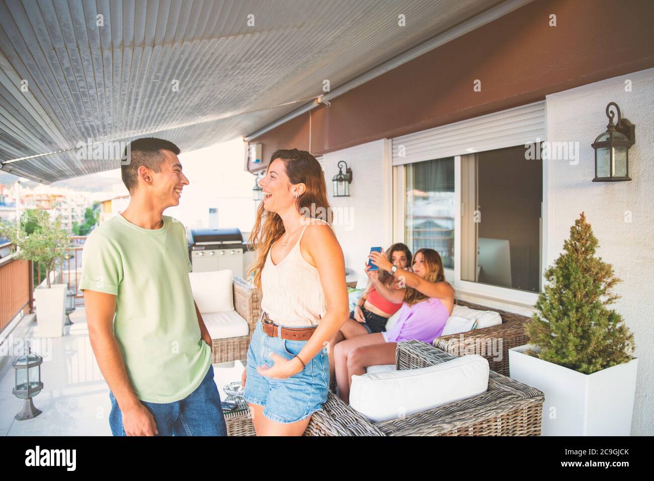 Happy Young Friends Talking and Laughing Outdoors on a Balcony. Concept with Friends Having Fun on a Balcony Stock Photo