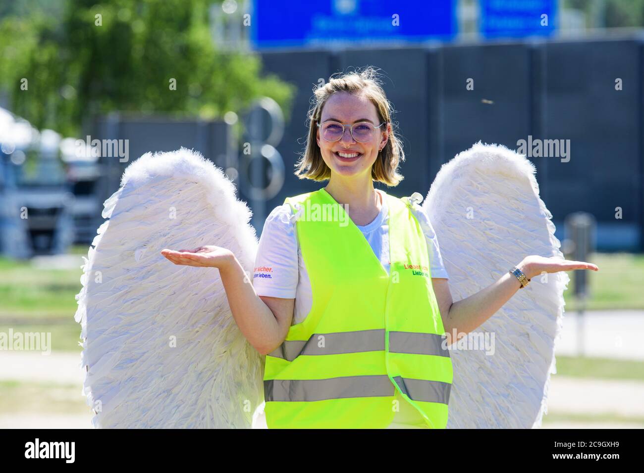 31 July 2020, Brandenburg, Michendorf: Emelie, dressed as guardian angel Jo, is standing on the grounds of the Michendorf-Nord rest stop. During the road safety campaign 'Lieber sicher. Lieber leben.', a tour of all Brandenburg motorway service stations is to draw attention to dangers in road traffic, especially during holiday trips. For this purpose, an information stand of the police, a model of an emergency lane, bobby car and sports course, a stand of the ADAC for reaction tests and a wheel of fortune will be set up. The road safety campaign has been in existence since 1997, and the guardi Stock Photo