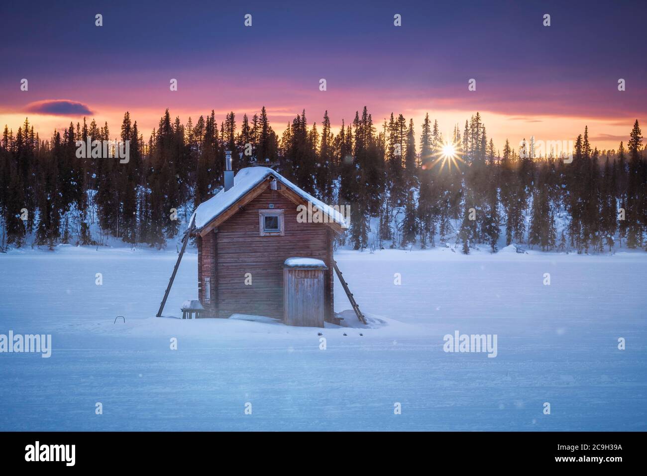 Small wooden hut against the light at extremely low temperatures at dawn, Skaulo, Norrbottens laen, Sweden Stock Photo