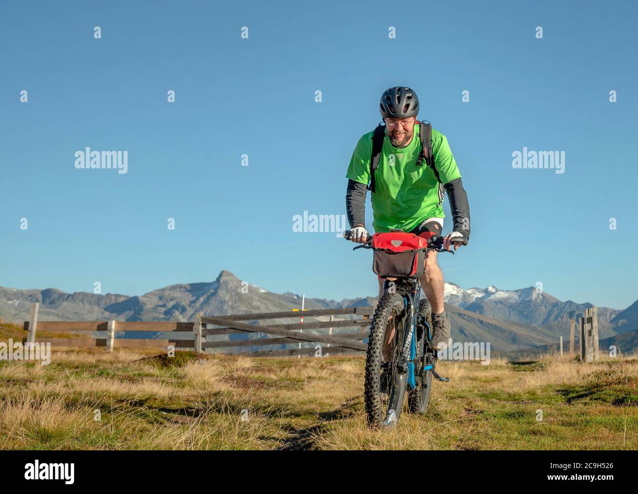 Mountain biker in his late forties rides on an ebike along an alpine path against a blue sky, Bergeralm leisure arena, bike park, Gries am Brenner Stock Photo
