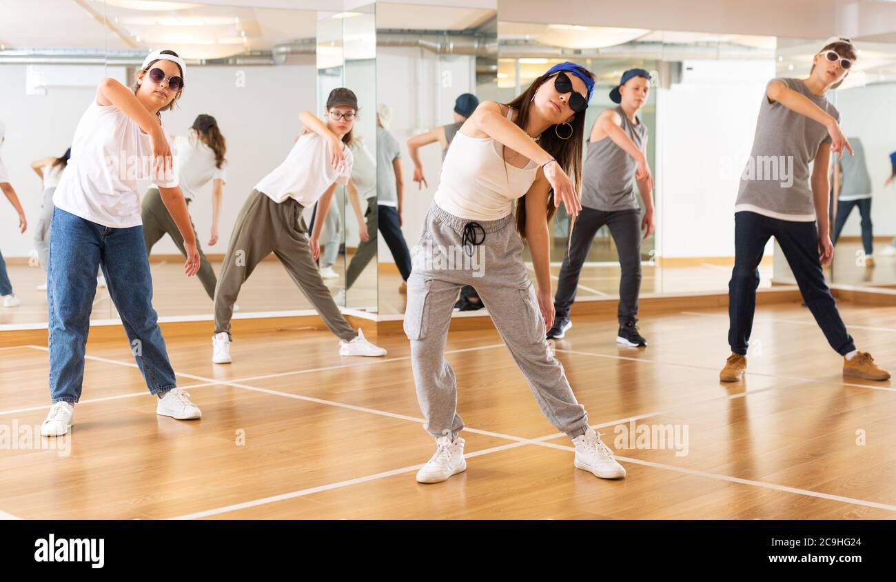Group of teenagers in casual clothes training hip-hop in class, learning modern dance movements Stock Photo