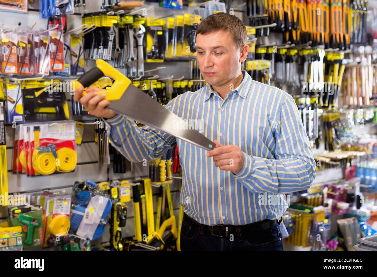 Glad positive  male customer choose bucksaw at hardware store Stock Photo