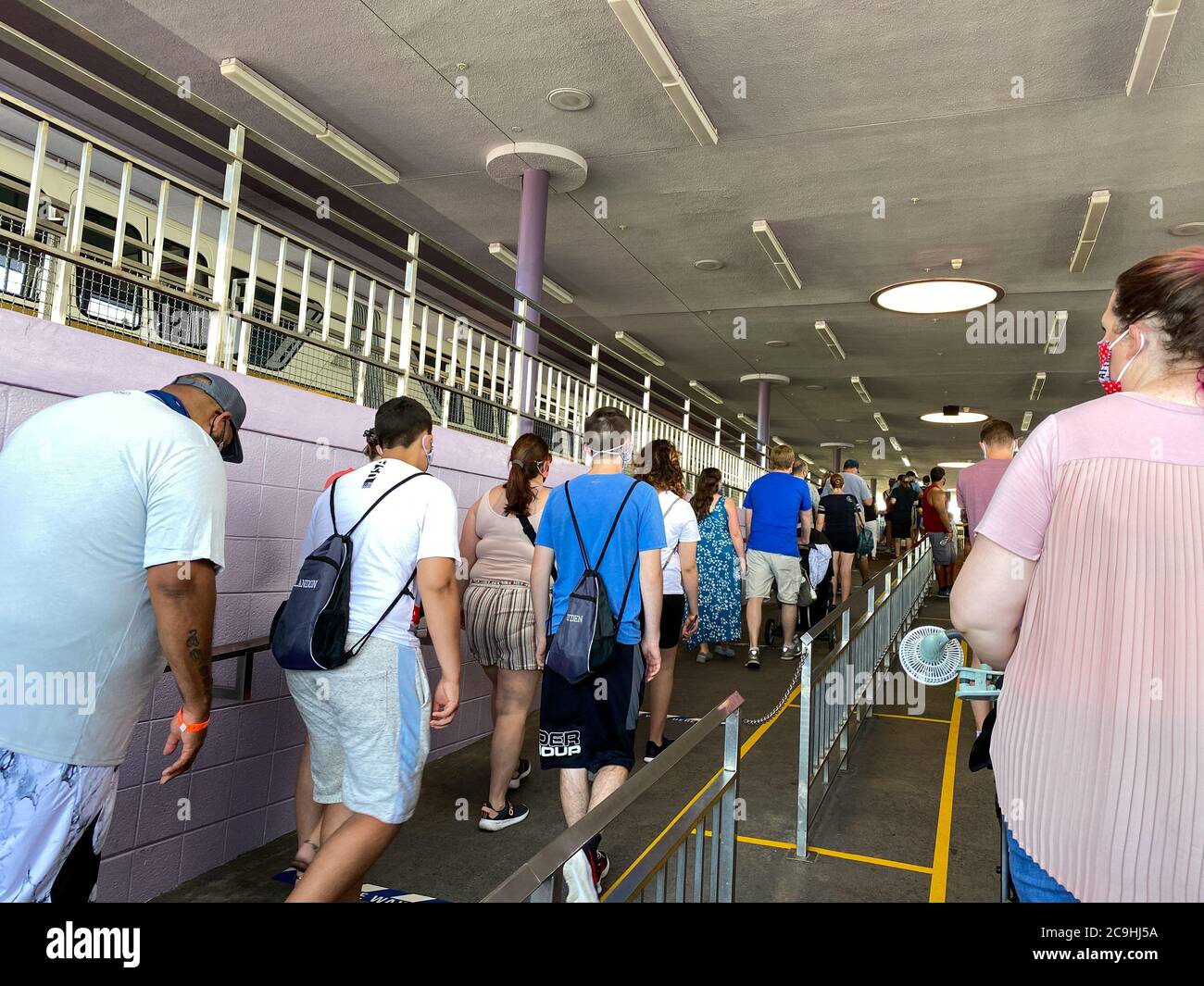 Orlando,FL/USA-7/25/20: People wearing face masks and social distancing while waiting in line to get on the monorail at  Walt Disney World Resorts in Stock Photo