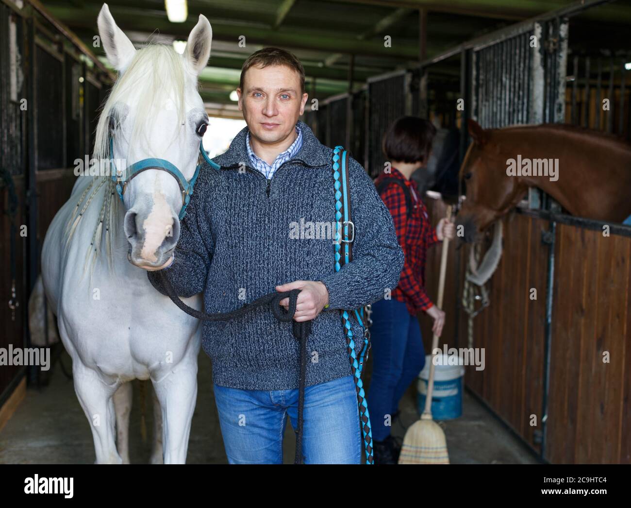 Portrait of cheerful man horse farm worker standing at stable Stock ...